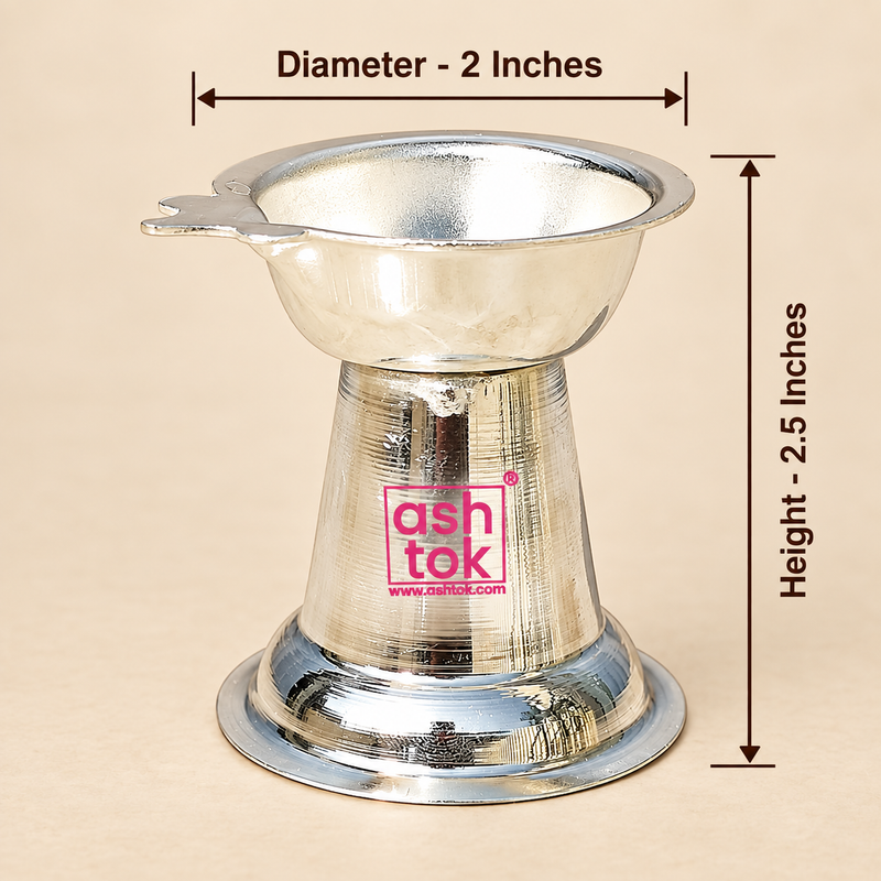 Size guide image of a German Silver Diya on a beige studio background with clear measurement arrows and text, showing the upper bowl diameter as 2 inches and the overall height as 2.5 inches, while also displaying the polished silver finish, shallow bowl design, side wick-holder extension, tapered conical center body and stable circular base, helping customers easily understand the compact product dimensions and proportions before purchase for pooja use, decorative use or gifting.