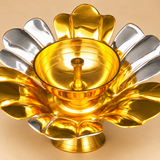 Detailed close-up of a gold and silver coated brass lotus diya showing the polished golden oil bowl, upright central wick holder, smooth circular rim, and alternating silver and gold lotus petals. The close-up highlights the reflective metal finish, carefully shaped decorative petals, and raised pedestal construction. This lotus-shaped brass oil lamp is designed for traditional pooja, Diwali decorations, festive ceremonies, and decorative religious arrangements.
