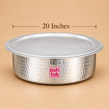 20 inch Aluminium Biryani Handi with Lid presented against a minimalist beige studio background with a clearly displayed 20 inches size label. The wide circular cooking vessel features a hammered silver aluminium exterior, matching flat circular lid, broad rolled rim and smooth rounded bottom. The metallic surface displays closely spaced circular hammered impressions that give the handi its traditional Indian cookware appearance. Designed for preparing larger quantities of Hyderabadi dum biryani.