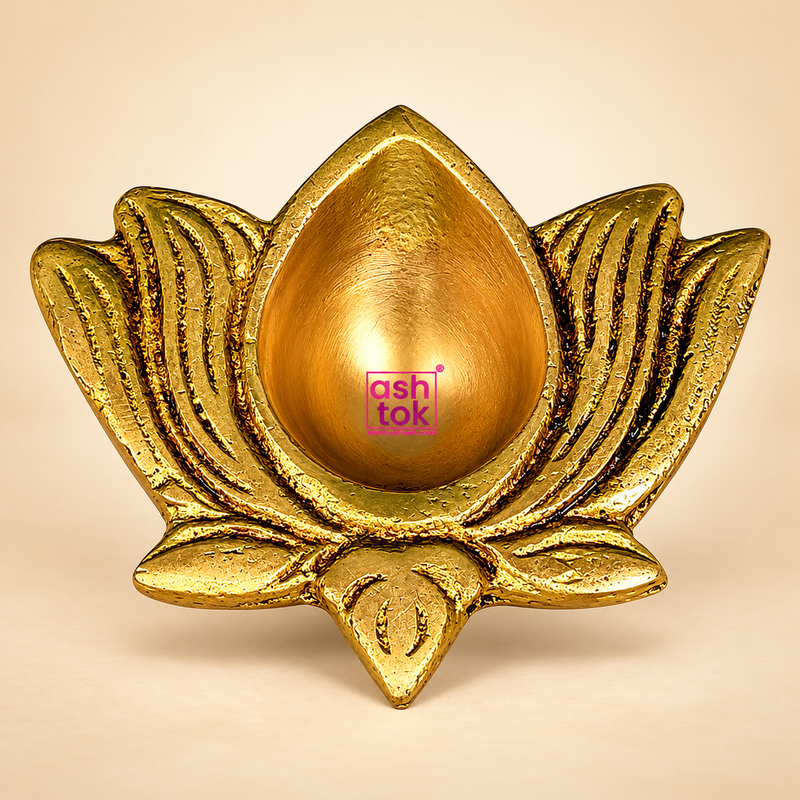 Traditional antique brass lotus diya featuring a central teardrop-shaped oil-holding cavity surrounded by beautifully sculpted lotus petals with engraved curved detailing. The decorative brass oil lamp has a golden antique finish, textured floral edges and a compact design suitable for daily puja, Diwali celebrations, home mandir decoration and traditional religious ceremonies.