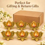 Six traditional antique brass lotus diyas arranged in front of a simple brown cardboard packaging box on a warm beige studio background. Each diya features a golden antique finish, sculpted lotus petals with detailed grooves and a smooth teardrop-shaped central cavity. The image demonstrates their suitability for wedding return gifts, festive gifting, housewarming celebrations, traditional religious ceremonies and bulk decorative orders.