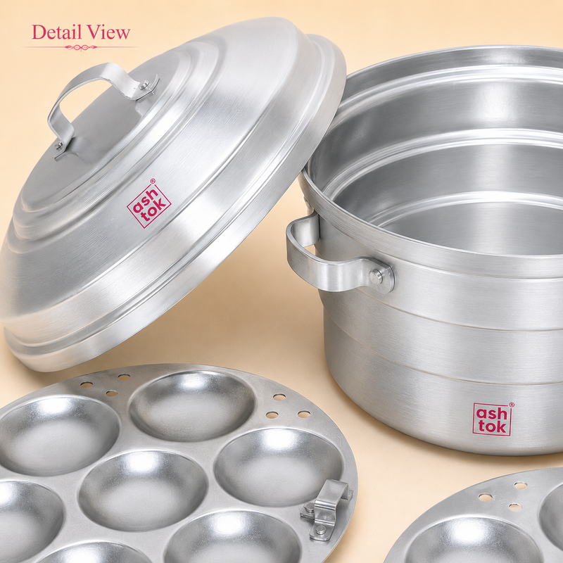 Close-up detail view of the Ashtok aluminium idli steamer pot, domed lid with top handle, side handle, and textured idli mold plates.
