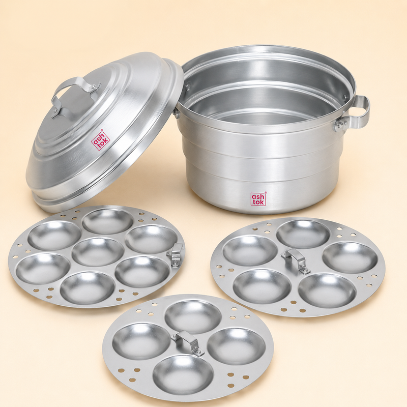 Ashtok aluminium idli steamer pot set with a lifted lid and three interchangeable idli plates containing 7, 5, and 4 cavities arranged in front.