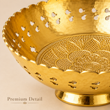 Close-up detail photograph highlighting the craftsmanship of an Ashtok brass decorative bowl. The image shows the scalloped upper rim, teardrop and oval cutouts along the sides, a hammered metallic interior finish, and an intricately embossed floral mandala pattern across the inner base. Small text in the bottom left reads "Premium Detail".