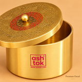 A close-up detail shot of the Ashtok brass container with its lid slightly off-center and tilted to reveal the interior rim. The image highlights the fine craftsmanship, showing the brushed metallic texture of the container side with the magenta logo, and the close details of the top lid’s intricate filigree engraving, red circular pattern, and central golden knob. "Premium Detail" text is subtly placed in the bottom right corner.