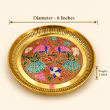 Product dimension diagram of the Ashtok round brass decorative tray against a warm studio background. Dimensional callout lines indicate a top outer diameter of 6 inches across the fluted rim and a side height of 1 inch. The center reveals intricate peacock Meenakari enamel artwork in pink, teal, blue, and red hues.
