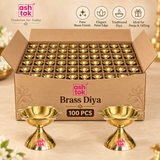 Ashtok brass diya 100 pcs bulk pack image showing a large open box filled with brass diyas and two brass diyas displayed in front on a beige studio background.