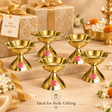 Ashtok brass diya bulk gifting image showing multiple polished brass diyas arranged in an elegant gifting setup with decorative gift boxes on a warm beige festive background.