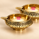 Close-up detail of ASHTOK brass diya pack of 2 showing the polished brass interior, decorative textured outer pattern and premium handcrafted finish on a beige background.