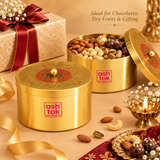 A festive product presentation featuring two Ashtok brass gift boxes. In the foreground sits a closed round brass container with an engraved lid and red center emblem. In the background, a second box is open to reveal four compartments filled with almonds, cashews, pistachios, and wrapped chocolates. The scene is decorated with a lit brass diya, loose dry fruits, a red ribbon, and a gift box tied with a satin bow. Headline text reads "Ideal for Chocolates, Dry Fruits & Gifting".