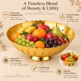An informative marketing graphic showcasing the design features and uses of the Ashtok brass decorative fruit bowl. The main image shows a large golden brass bowl on a pedestal base filled with fresh fruits, including apples, oranges, bananas, pomegranates, grapes, and a pear. Visual callout circles highlight five key features: "Decorative Scalloped Rim" for elegance, "Pierced Cutout Design" for a unique look, "Engraved Base Pattern" for rich traditional appeal, "Gold Finish" providing a luxurious shine, an