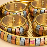 Close-up detail of ASHTOK brass gift tray and bowls showing the polished hammered finish, textured multi-tone gold, copper and silver pattern, matching lids and premium decorative craftsmanship.