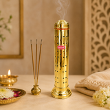 Ashtok brass incense stick holder emitting fragrance smoke, set on a prayer altar next to incense sticks, oil lamp, and flowers.