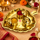 ASHTOK brass leaf shaped kumkum box set styled in a traditional festive pooja setting, with the polished brass leaf tray holding three matching containers and selected boxes opened to display red kumkum and yellow haldi powder. The scene includes warm diya lighting, marigold flowers, jasmine flowers, rose petals and traditional festive decor, demonstrating how the set can be used for daily pooja, haldi kumkum ceremonies, religious rituals, festive occasions and gifting.