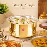 Ashtok brass Patila filled with garnished rice on a dining setup alongside curry dishes.