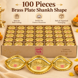Bulk gifting image of 100 pieces of the Ashtok brass plate shankh shape presented in a large organized box for wholesale and event gifting purposes. The image shows numerous identical brass shankh plates arranged neatly in individual cardboard compartments, with three larger pieces displayed prominently in the foreground to show product clarity and design details. Each plate features a bright polished brass finish, elegant shell-inspired shankh shape, scalloped edge, embossed decorative lines and the origin