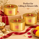 A promotional image featuring three Ashtok brass gift containers arranged in a festive setting with the text "Perfect for Gifting & Return Gifts". One box rests atop a brown wrapped gift box with a red satin bow, while two others sit alongside traditional Indian festival decor including jasmine flowers, a brass oil lamp (diya), loose yellow and red flower petals, and a red ribbon trailing across the warm beige background.

Image 6