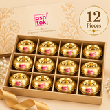 Pack of 12 Ashtok Brass Sindoor Boxes displayed in an elegant compartmentalized beige presentation box, arranged in three rows of four polished brass containers for a clear representation of the 12 piece quantity option. Each traditional brass sindoor dabbi has a premium glossy golden finish, compact round body, matching fitted lid, small top knob and original pink Ashtok branding. The decorative packaging presentation demonstrates how these compact brass kumkum containers can be used for wedding return gif