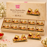 Pack of 100 image of Ashtok brass sindoor box double duck design showing ten brass sindoor boxes neatly packed inside a gift box with compartments, with product branding and elegant presentation suitable for return gifts and festive gifting.