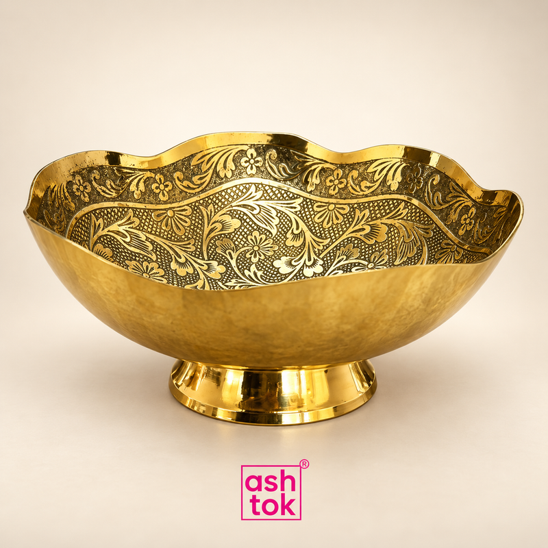 Ashtok Brass Turkish Bowl displayed as a clean standalone product image on a warm beige studio background, featuring a wide decorative bowl with an elegant scalloped rim, rich golden brass finish, intricate floral and leaf engraving across the inner surface, smooth curved outer body and a polished raised pedestal base. The traditional ornamental pattern and premium metallic appearance make this decorative brass bowl suitable for serving dry fruits, nuts, sweets and chocolates, as well as festive table decor