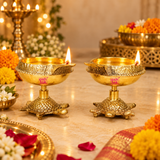 Festive lifestyle image of brass diyas with turtle bases styled with marigold flowers and traditional decor, showing how the diya can be used for pooja rituals, Diwali decoration, and spiritual home settings.