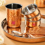 Close-up detail shot of Ashtok copper dinner set featuring stacked hammered copper bowls, tumbler, tray, and matching spoon with dual-tone copper and stainless steel finish.