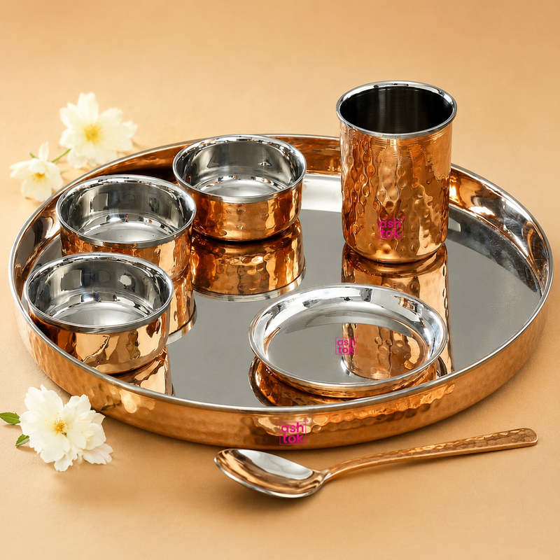 Ashtok 7-piece copper dinner set featuring a hammered copper tray, three bowls, a tumbler, a small plate, and a matching spoon with stainless steel interiors.