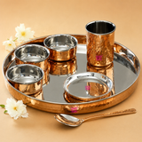 Ashtok 7-piece copper dinner set featuring a hammered copper tray, three bowls, a tumbler, a small plate, and a matching spoon with stainless steel interiors.