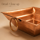 Close-up view of an Ashtok copper Havan Kund showing the sturdy side ring handle, stepped interior walls, and polished copper finish.