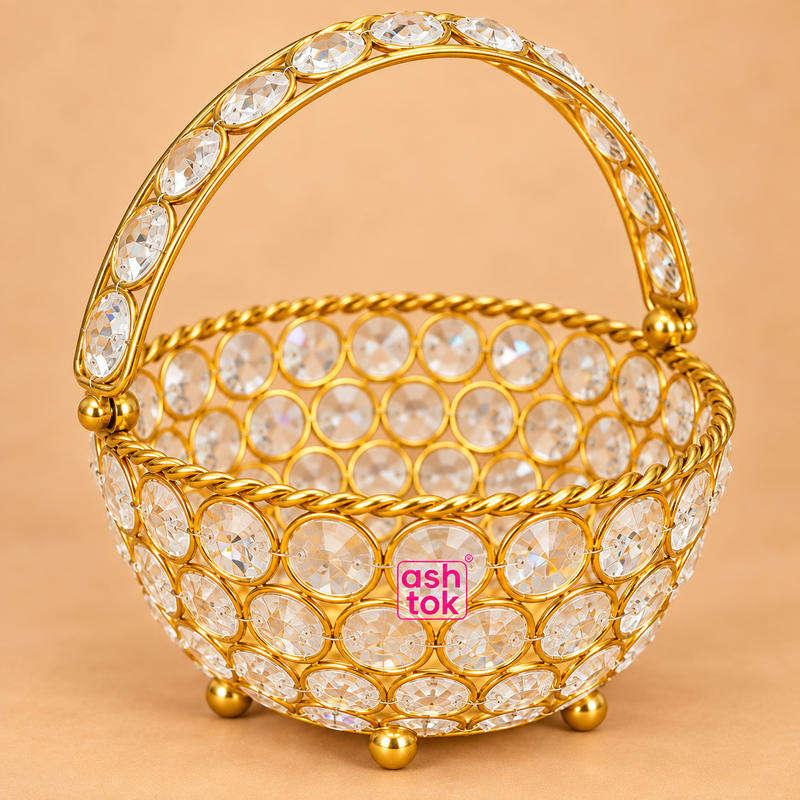 Close-up detail image of Ashtok crystal basket gift item showing the gold finish frame, circular crystal embellishments, arched crystal handle and premium decorative craftsmanship on a beige background.