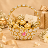 Lifestyle usage image of Ashtok crystal basket gift item filled with chocolates and decorative floral accents, showing the elegant basket being used for festive gifting and presentation on a beige styled background.