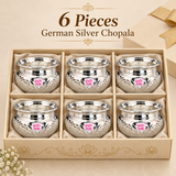 Set of 6 Ashtok German Silver Chopala Haldi Kumkum Boxes arranged neatly inside a premium beige presentation box with individual compartments and soft cushioned lining. Each chopala features a polished German silver finish, wide flared rim, rounded embossed body, decorative floral detailing and clearly visible pink Ashtok logo on the front. The six matching bowls are displayed together to represent the 6 piece quantity option, making this set suitable for wedding return gifts, haldi kumkum functions, pooja 