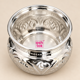 Detailed close-up view of the Ashtok German Silver Chopala Haldi Kumkum Box shown from a slightly elevated top angle on a clean beige studio background. The close-up highlights the smooth polished interior, wide flared silver rim, reflective German silver finish, intricate embossed floral and scroll patterns around the inner and outer body, fine beaded decorative detailing and the compact rounded form of the bowl. The original pink Ashtok logo is clearly visible, while the close framing helps customers insp