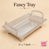 Ashtok German silver fancy tray in 11 x 7 inch size displayed on a beige background, showcasing a compact rectangular tray with fine openwork filigree borders, polished silver shine, bead-style handles, raised feet, and a reflective base, making it ideal for serving dry fruits, chocolates, sweets, return gift presentation, festive décor, and elegant table styling in a smaller size format.