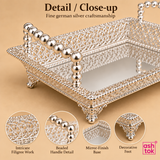 Close-up detail image of the Ashtok German silver fancy tray highlighting the delicate filigree craftsmanship, polished silver finish, textured ornamental edgework, bead-style side handle detailing, small raised decorative legs, and reflective tray base, giving a clear view of the fine handcrafted look and premium finishing that make this tray suitable for elegant serving and gifting.