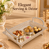 Lifestyle presentation image of the Ashtok German silver fancy tray styled as an elegant decorative serving accessory, shown on a beige background to highlight its ornamental filigree body, mirror base, classic silver finish, and premium handcrafted look, making it suitable for serving sweets, chocolates, dry fruits, snacks, gift hampers, festive table décor, and stylish home entertaining.