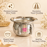 Features infographic of the ASHTOK German Silver handi and sweet bowl highlighting its premium German silver finish, decorative tassel detailing, elegant sweet bowl design and suitability for serving and gifting. The image shows the polished reflective bowl on a warm beige background with its hammered body, flared scalloped rim, twisted rope-style band and pink ASHTOK branding clearly visible.