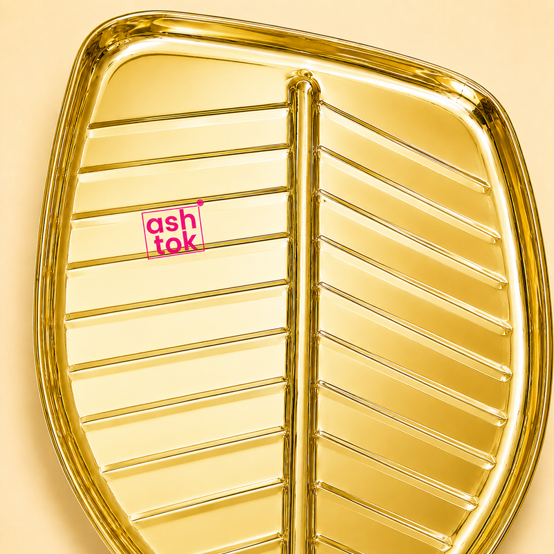 Close-up detail of the Ashtok golden leaf tray showing its smooth metallic surface, raised outer rim, and embossed vein lines.