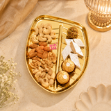 Ashtok golden leaf tray styled with assorted dry fruits, nuts, chocolates, and Indian sweets in an elegant festive setup.