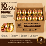 Promotional advertisement graphic for Ashtok Gold Plated Surai 100 Pcs Value Pack. A large cardboard box is filled with rows of small, hammered gold-plated surai containers, each capped with a rose-gold/copper metallic lid topped with a decorative gold flower finial. To the lower left, an enlarged single surai jar stands next to its lid. Text headers proclaim "BULK ORDER • BETTER VALUE", "100 PCS VALUE PACK", and "WHAT YOU GET: 100 Pieces in Total". Bottom feature badges note "100 PCS IN TOTAL", "INDIVIDUAL