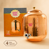 Ashtok 4-litre hammered copper water matka dispenser with top lid and tap, positioned next to its packaging box.