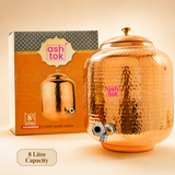 Ashtok 8-litre capacity hammered copper water pot dispenser with tap placed beside its printed retail box.