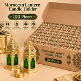 Bulk wholesale image of the Ashtok Moroccan Lantern Candle Holder showing a large carton-style organized box filled with multiple individual lantern units arranged in neat compartments, representing the 100 piece quantity option. In the foreground, a few lanterns and one removable candle cup are displayed clearly to show the product shape, green glass panel design, perforated Moroccan cutwork and gold metal finish, while the open bulk box in the background illustrates large-scale packaging suitable for whol