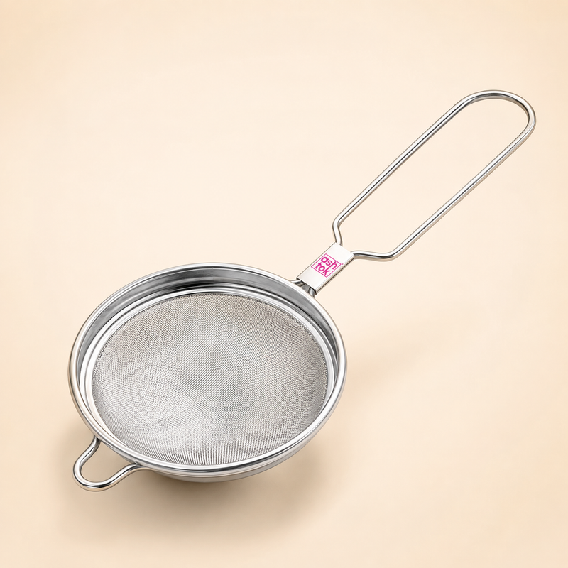 Full product view of an Ashtok stainless steel tea strainer featuring a long wire handle, rest hook, and fine mesh filter.
