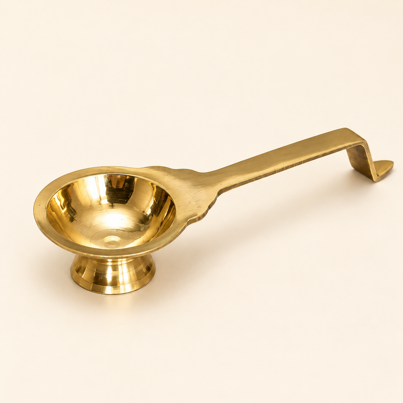 Brass Aarti Diya with long handle and pedestal base on beige background.