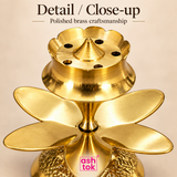 Close-up of brass agarbatti stand showing polished brass craftsmanship, incense holes, central spike and lotus petal design.