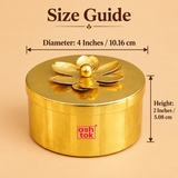 Size guide of a round brass coloured metal dry fruit gift box showing a diameter of 4 inches or 10.16 cm and height of 2 inches or 5.08 cm. The decorative container features a polished golden finish, smooth cylindrical body and removable flat circular lid topped with an elegant layered flower design and spherical golden knob. Suitable for compact dry fruit storage and traditional festive gifting.