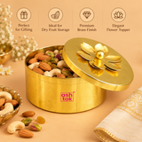 Product features infographic showcasing a traditional brass coloured metal dry fruit gift box with a polished golden finish, round cylindrical storage body and decorative floral lid topped with a spherical knob. The image highlights its reusable lidded storage design, elegant flower-shaped topper, compact dimensions and suitability for storing assorted dry fruits, festive sweets, wedding return gifts and special occasion gifting.