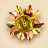Top view of a decorative brass and copper lotus diya on a soft beige background, clearly showing the symmetrical arrangement of alternating golden brass and copper lotus petals surrounding a polished round brass oil bowl with central wick holder, with the layered petal construction and reflective metallic finish visible in detail, making the image useful for showcasing the diya design for daily pooja, festive decoration, spiritual rituals, home temple styling and traditional Indian gifting.