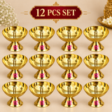 Set of 12 traditional brass diyas displayed in an organized beige studio arrangement, featuring matching polished brass oil lamps with central wick holders and pedestal bases for Diwali celebrations, religious functions and bulk gifting.